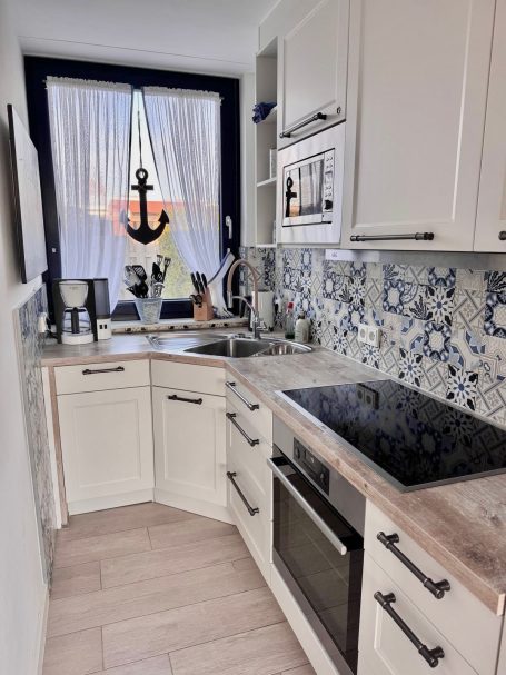 Eine U-Förmige Küchenzeile mit Fenster nach draußen. Filterkaffeemaschiene und Herd sind gut zu erkennen. 