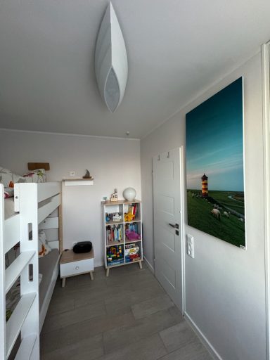 Ein Etagenbett im zweiten Schlafzimmer. Rechts daneben steht ein Nachttischchen und ein Schrank mit Spielsachen. Daneben die Tür.