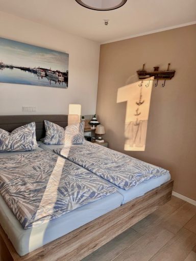 Ein Doppelbett im Schlafzimmer mit Lämpchen auf den Nachttischen auf beiden Seiten. An der Wand sind Kleiderhaken angebracht.