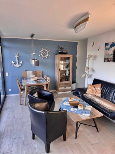 Wohn- / Essbereich. Wieder das Doppelsofa und Sessel. Im Hintergrund ein Esstisch, Vier Stühlen, Vitrine mit Gläsern, Maritime Deko.