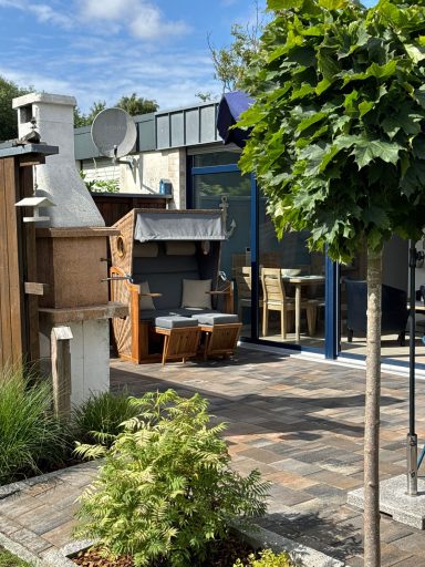 Eine Nähere Aufnahme des Strandkorbs der vor der Fensterfront steht. Auch der Kamingrill ist zu sehen.