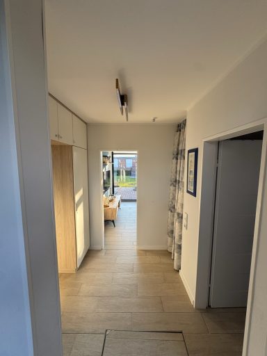 Der Flur zum Wohnbereich aus der Perspektive wenn man rein kommt. Links und rechts gehen Türen ab und vorne sieht man raus bis in den Garten