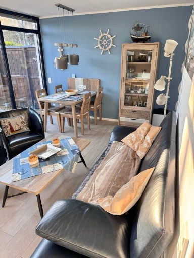 Wohn- / Essbereich. Wieder das Doppelsofa und Sessel. Im Hintergrund ein Esstisch, Vier Stühlen, Vitrine mit Gläsern, Maritime Deko.